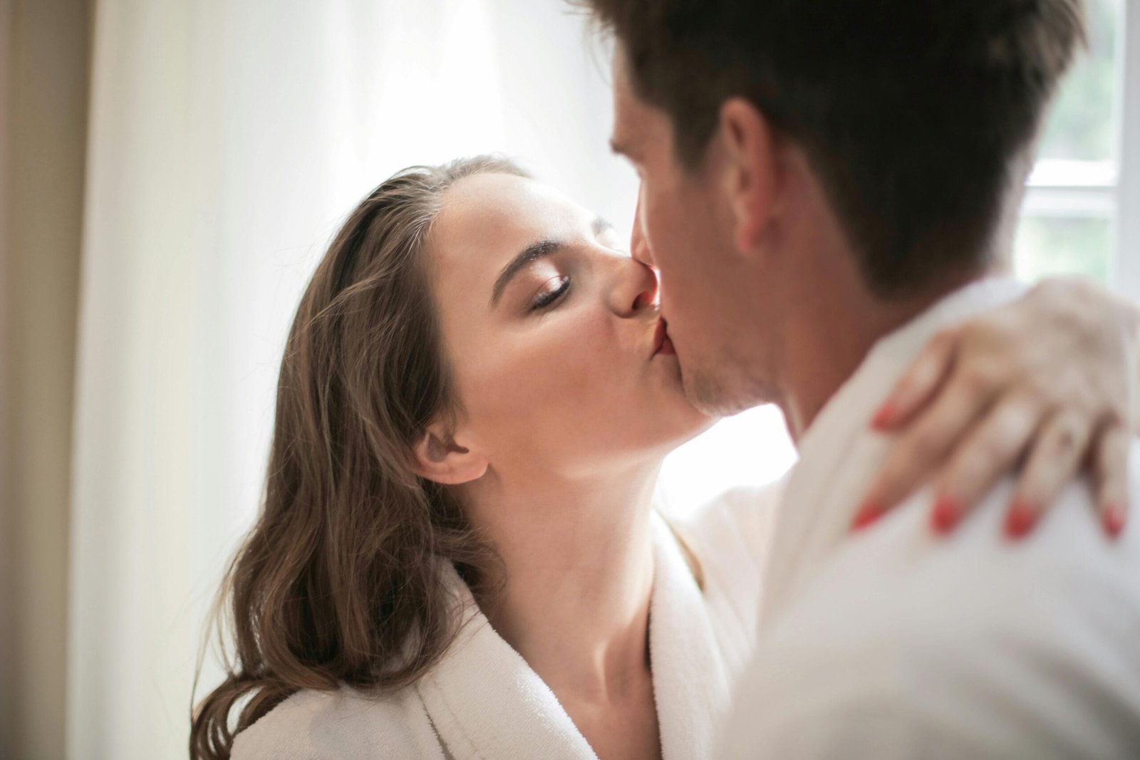 A loving couple shares a tender kiss indoors, capturing intimacy and affection.