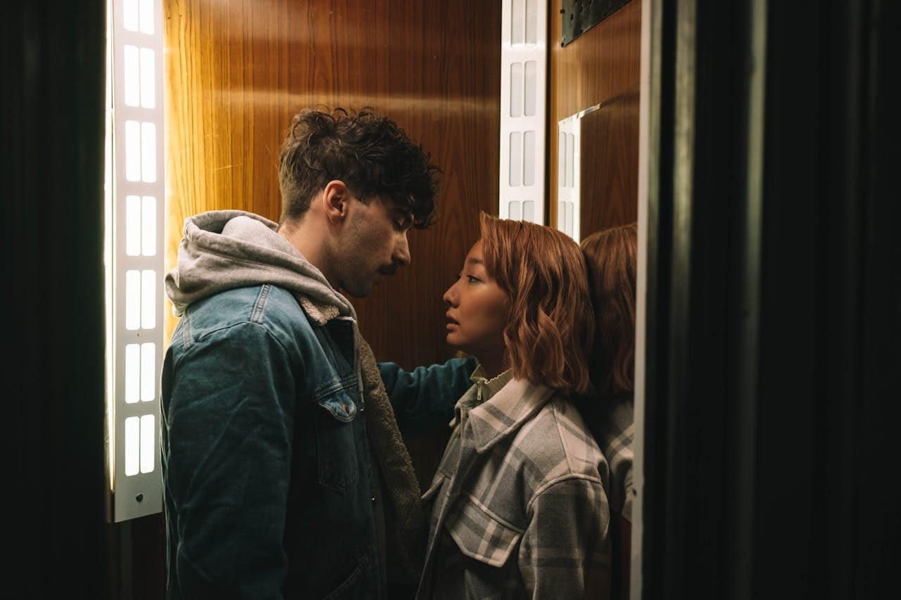 Couple sharing an intimate moment inside a warmly lit elevator.